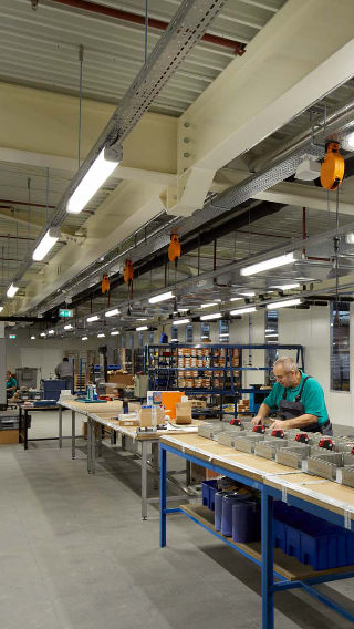 Seorang karyawan bekerja di area produksi Venco Campus, diterangi dengan pencahayaan industri Philips