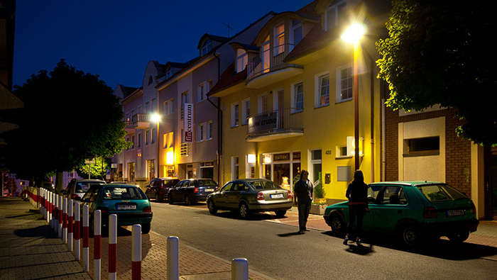 Orang-orang berjalan di jalan pada malam hari di bawah pencahayaan jalan Philips 