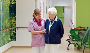A nurse taking care of an elderly lady in a lit up hallway