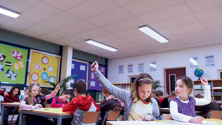 Anak-anak asyik dalam pelajaran mengangkat tangan mereka untuk menjawab pertanyaan dari seorang guru - lingkungan belajar yang optimal