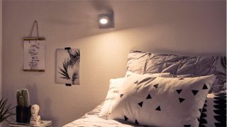 Kamar tidur bergaya dengan lampu sorot LED yang dapat disesuaikan menciptakan suasana nyaman, menerangi tempat tidur geometris dan dekorasi minimalis.